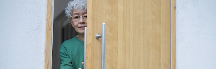 玄関を開ける高齢女性